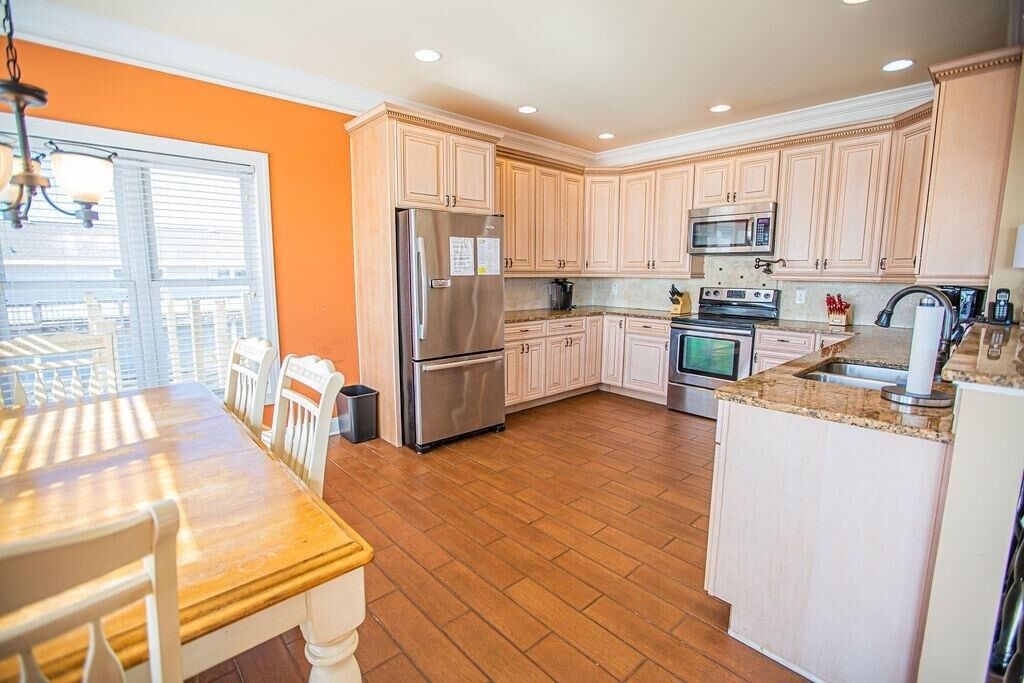 A kitchen with wooden cabinets, a stainless steel refrigerator, a microwave, and an oven.