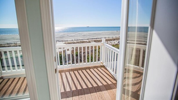 A balcony with a view of the beach and ocean.