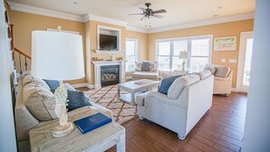 A living room with a fireplace, two sofas, a coffee table, and a ceiling fan.