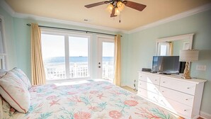 A bedroom with a bed, a dresser, a television, and a ceiling fan.
