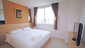 Une chambre d’hôtel avec un grand lit, un téléviseur à écran plat et une fenêtre avec des rideaux.