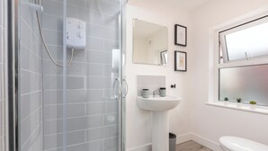 Un baño moderno con cabina de ducha de vidrio, lavabo pedestal y inodoro.