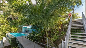 A wooden deck leading to a swimming pool surrounded by lush greenery and a staircase. - Villa Mar y Sol: 4 Independent Apartments in Quiet, Natural Area w/ wildlife! (Manuel Antonio)