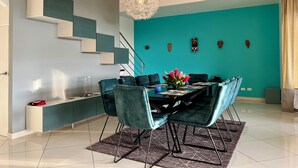 A modern dining area with teal walls, a staircase, and decorative wall art. - Villa Mar y Sol: 4 Independent Apartments in Quiet, Natural Area w/ wildlife! (Manuel Antonio)