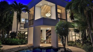 A modern two-story house with a swimming pool, surrounded by tropical plants and palm trees. - Turtle Breeze - Fully Staffed Oceanfront Villa with Private Chef (Turtle Cove)