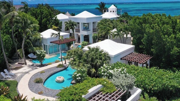 A resort with a pool, white buildings, and a view of the ocean. - Turtle Breeze - Fully Staffed Oceanfront Villa with Private Chef (Turtle Cove)