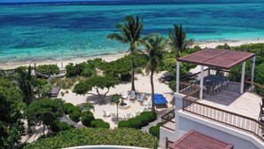 A beachfront property with a covered outdoor seating area, a pool, and a view of the ocean. - Turtle Breeze - Fully Staffed Oceanfront Villa with Private Chef (Turtle Cove)