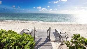 A beach with a wooden walkway leading to lounge chairs. - Turtle Breeze - Fully Staffed Oceanfront Villa with Private Chef (Turtle Cove)