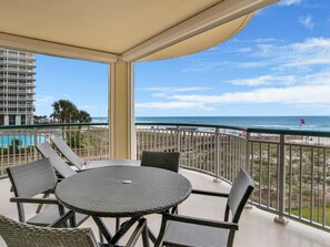 Ein Balkon mit Rattanmöbeln mit Blick auf Strand und Pool.
