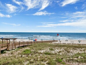 A beach with a wooden boardwalk, beach chairs, and umbrellas.