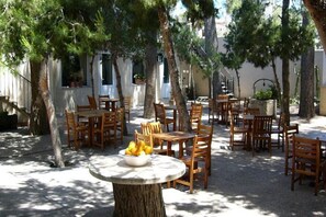 An outdoor seating area with multiple wooden tables and chairs, surrounded by trees. - Hotel Torre San Juan (San Juan de Alicante)