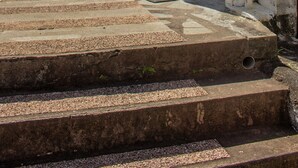 A set of concrete steps leading up to a gated entrance with a cross and a building with a blue and white facade. - T2 - 66m2 - Résidence Georgette ☆☆☆☆ (SAINT-PIERRE)