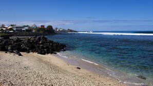 A beach with clear waters, a rocky shoreline, and buildings in the background. - T2 - 66m2 - Résidence Georgette ☆☆☆☆ (SAINT-PIERRE)