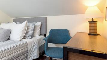 A hotel room with a bed, a chair, a table, and a lamp.