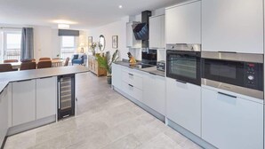 A modern kitchen with white cabinets, a built-in oven, and a microwave.