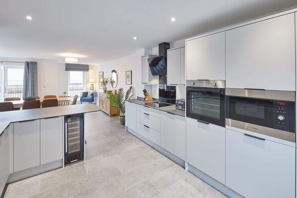 A modern kitchen with white cabinets, a built-in oven, and a microwave.
