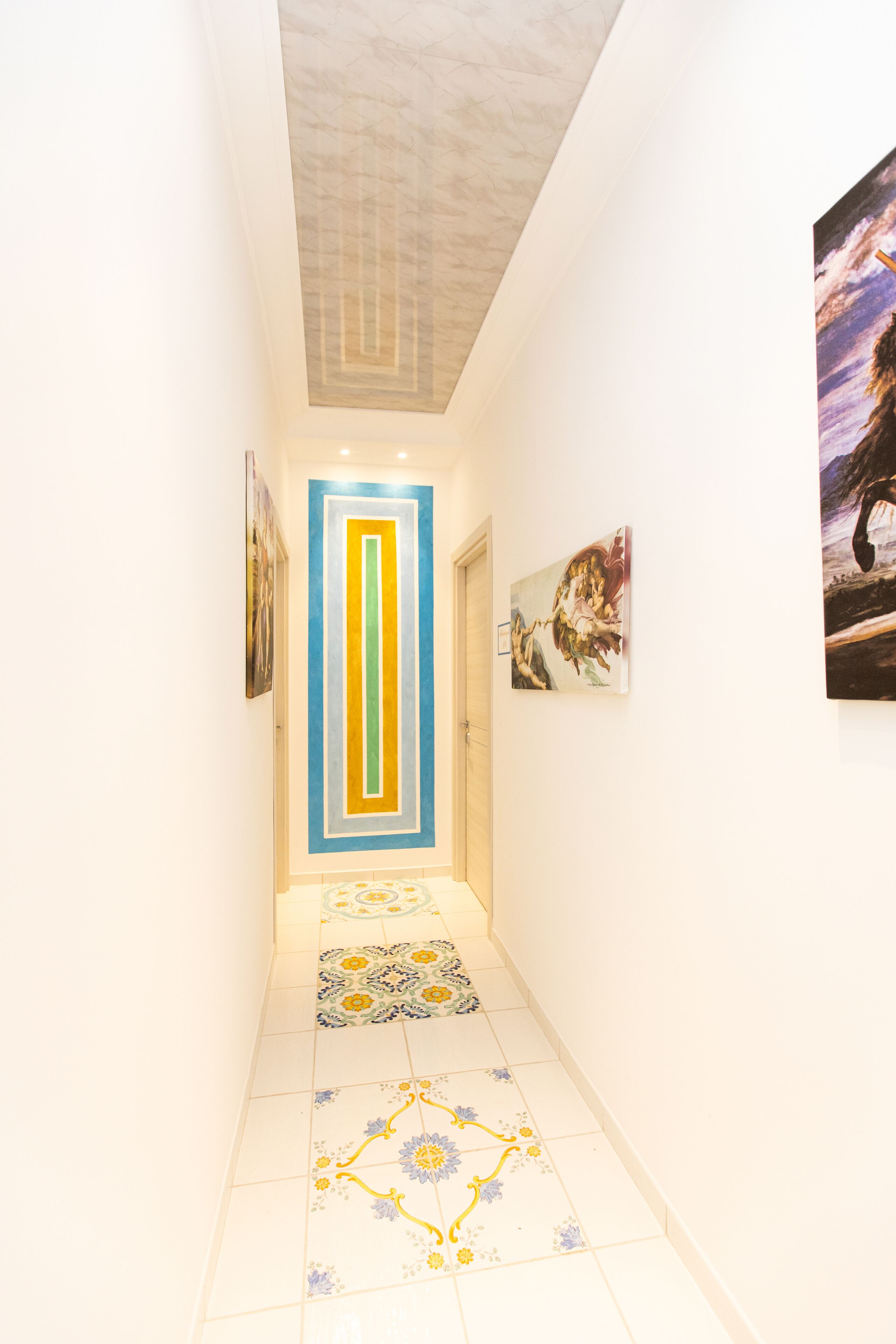 A hallway with a patterned floor, a door with a geometric design, and artwork on the walls.