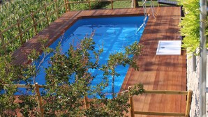 A rectangular swimming pool with a wooden deck and metal railings, surrounded by lush greenery and trees. - Panariello Palace (Agerola)