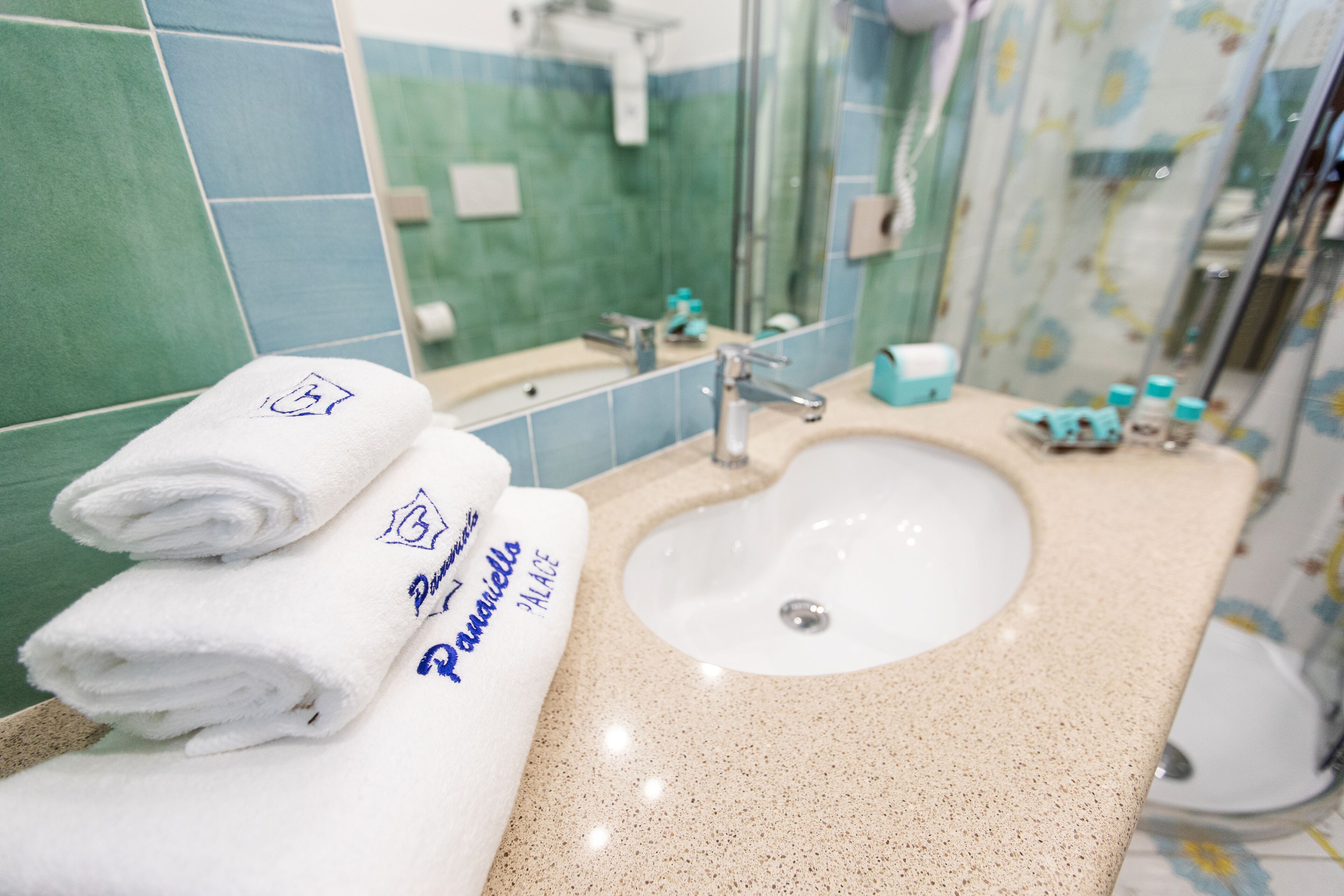 A bathroom with a sink, mirror, and towels.