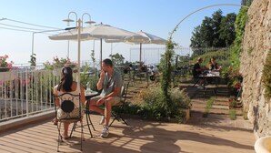 An outdoor patio with tables and chairs, surrounded by a white fence and potted plants. - Panariello Palace (Agerola)