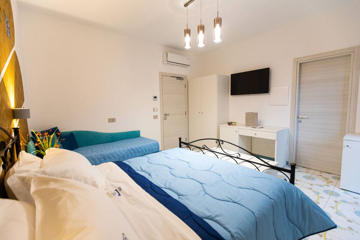 A bedroom with a bed, bedside table, and a TV mounted on the wall.