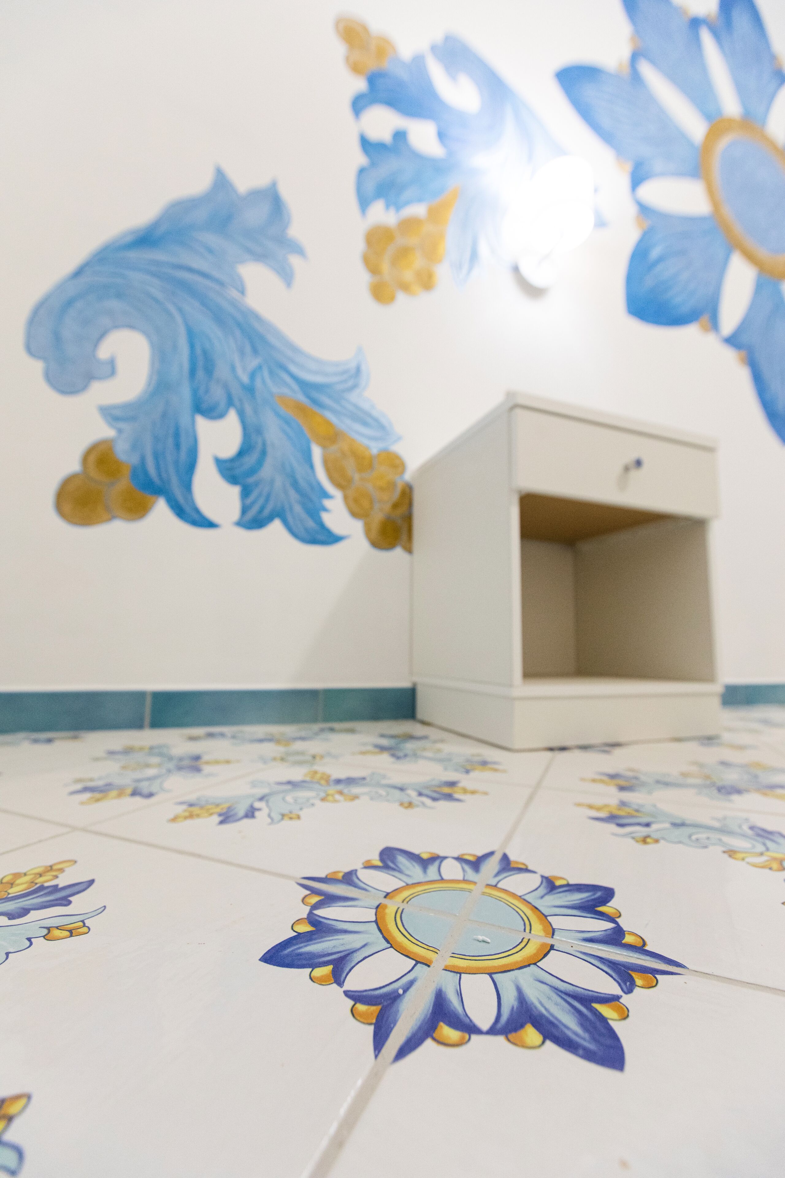 A room with a white cabinet and a tiled floor with floral patterns.