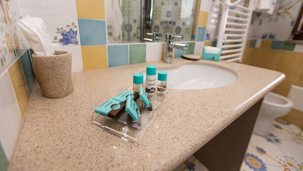 A bathroom with a sink, mirror, and toiletries on the counter. - Panariello Palace (Agerola)