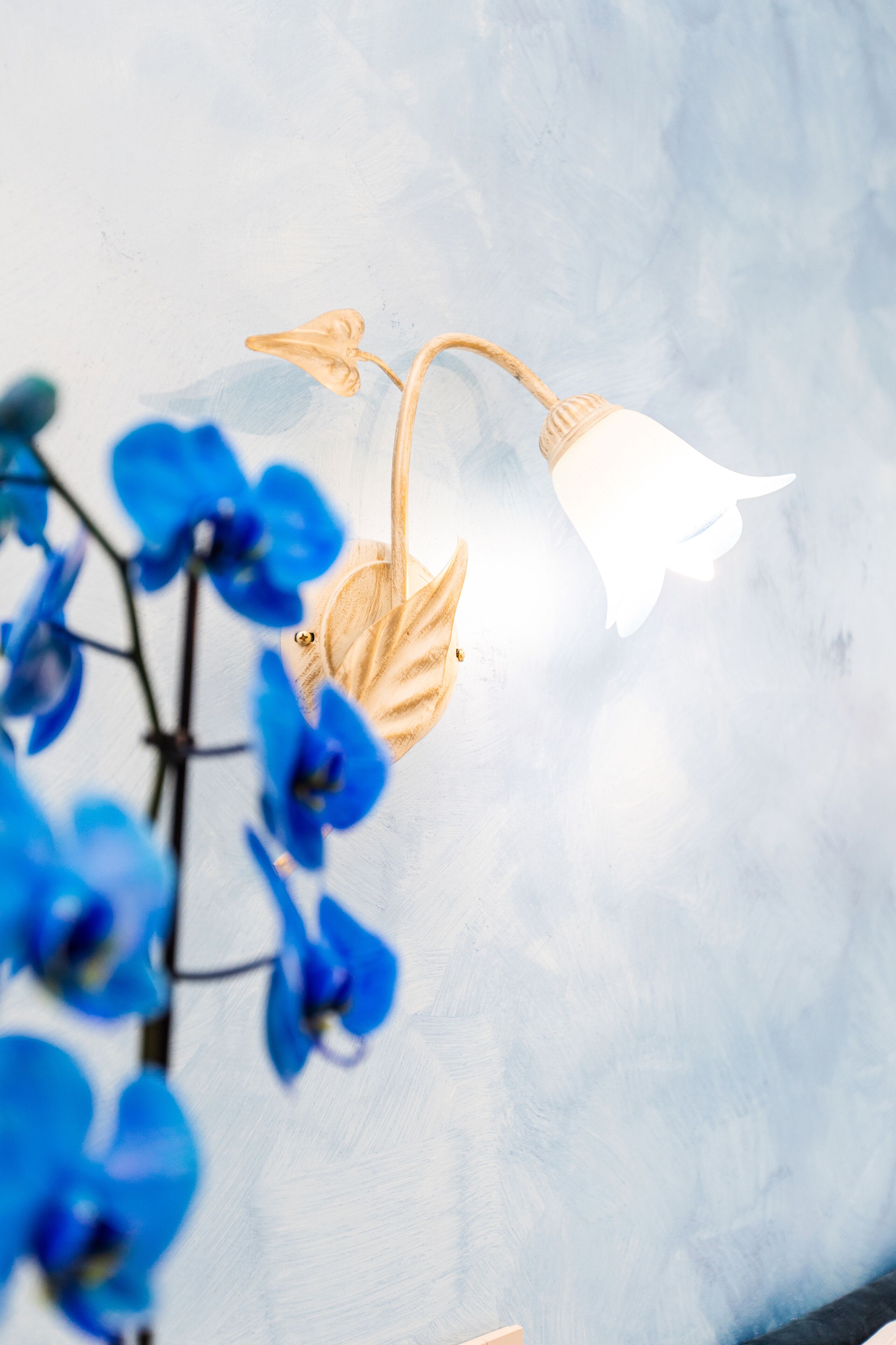 Un luminaire mural orné d’un motif de feuille et doté d’un abat-jour blanc.