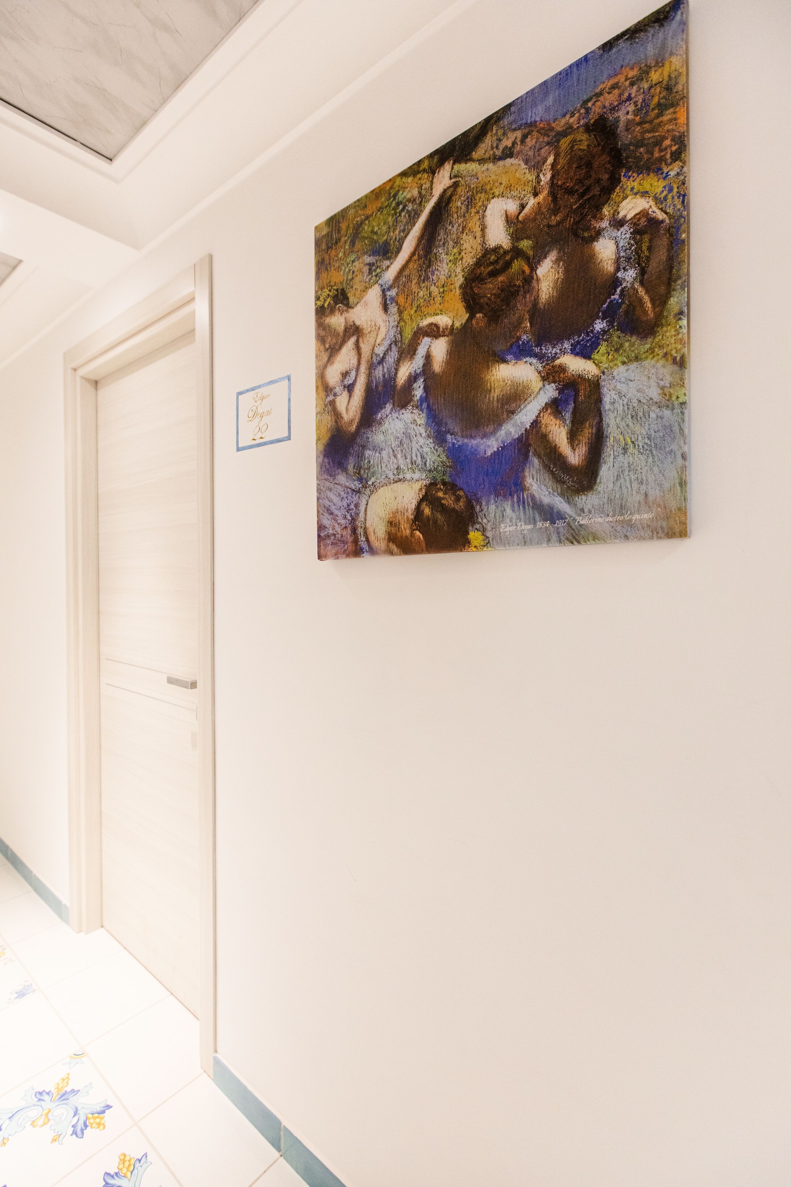 Un couloir orné d’un tableau représentant une figure nue et muni d’une porte.