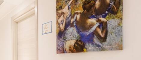 A hallway with a painting of a nude figure and a door.