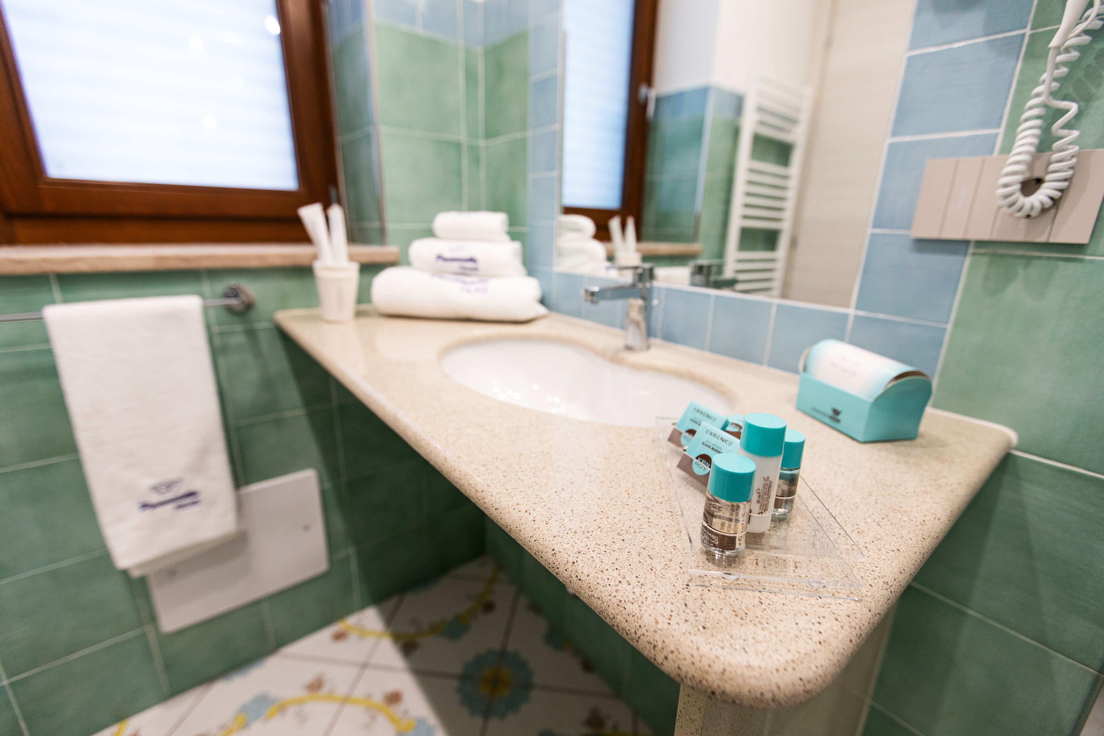 A bathroom with a sink, mirror, and toiletries.
