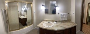 A bathroom with a marble sink, a large mirror, and two wall-mounted lights.