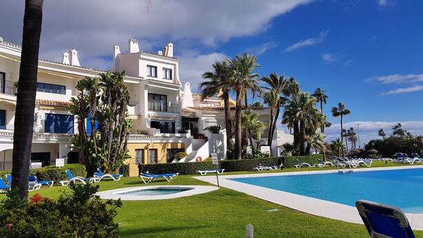 Un resort con piscina, palmeras y un edificio grande con balcones.