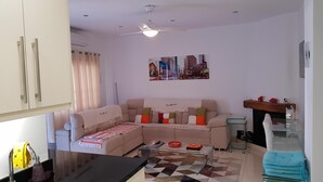 Una sala de estar con un sofá, una mesa de centro, un cuadro y un ventilador de techo.