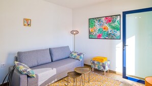 A living room with a grey sofa, a small round table, a floor lamp, and a colorful artwork on the wall. - D13-2 Cabopino (Marbella)