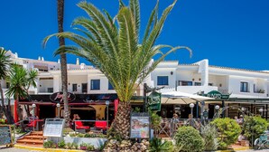 A coastal restaurant with outdoor seating, palm trees, and a clear blue sky. - D13-2 Cabopino (Marbella)
