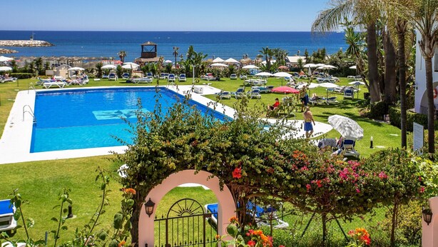 Zona piscina con vista mare, circondata da ombrelloni e lettini.