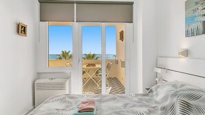 Una camera da letto con un letto grande, una finestra vista spiaggia e un ventilatore a soffitto.