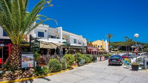 A cobblestone street lined with palm trees and outdoor seating at various cafes. - K105 Cabopino (Marbella)