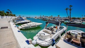 A marina with various boats docked, a clear blue sky, and palm trees in the background. - K105 Cabopino (Marbella)