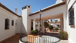 A courtyard with a central fountain, potted plants, and a tiled floor. - K105 Cabopino (Marbella)