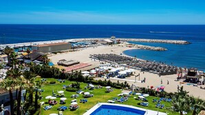 A coastal resort with a swimming pool, beach area, and marina.