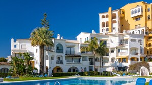 Un hotel con piscina, palme e cielo azzurro.