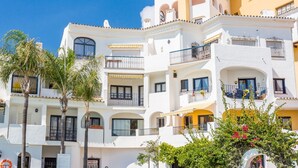 A multi-story building with balconies, white walls, and a clear blue sky. - L168 Cabopino (Marbella)