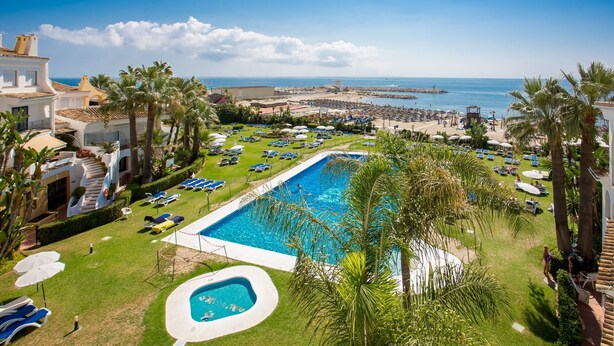 A resort with a large swimming pool, a beach, and a view of the sea. - L168 Cabopino (Marbella)
