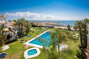 A resort with a large swimming pool, a beach, and a view of the sea. - L168 Cabopino (Marbella)