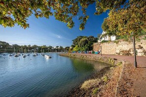 Un rivage paisible, avec des bateaux, un mur de pierre et un sentier.