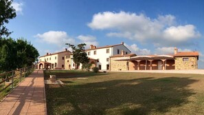 A large, historic building with multiple arches and a paved pathway leading to it.