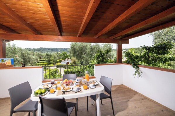 A breakfast table set on a balcony with a view of a lush landscape. - Apartment "2-roomed" first floor for 2/3 person (Vieste)