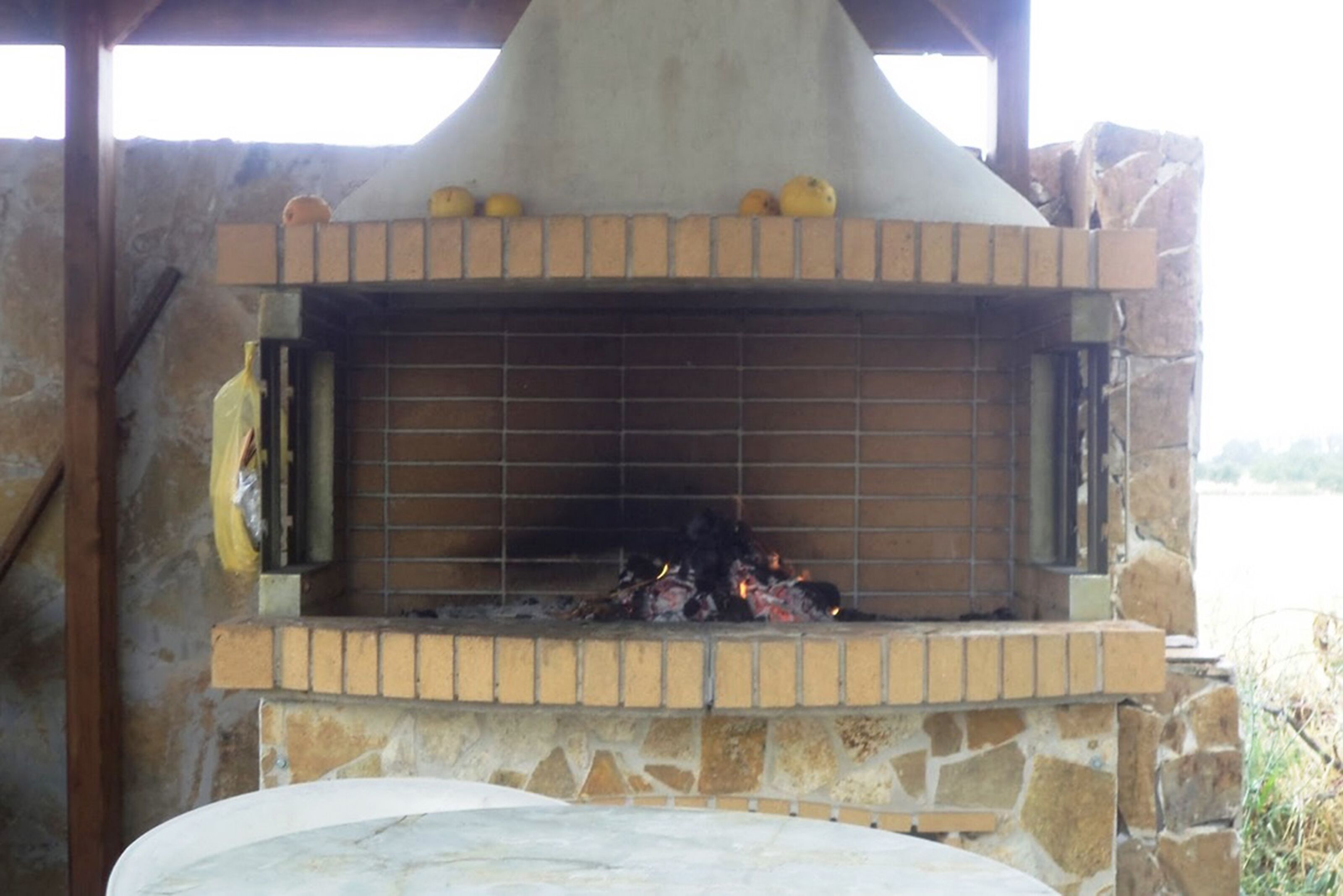 A stone-built outdoor oven with a brick base and a metal grate.